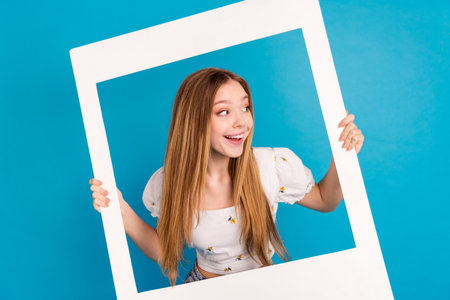 Photo of nice young girl album card look empty space wear top isolated on blue color backgroundの写真素材