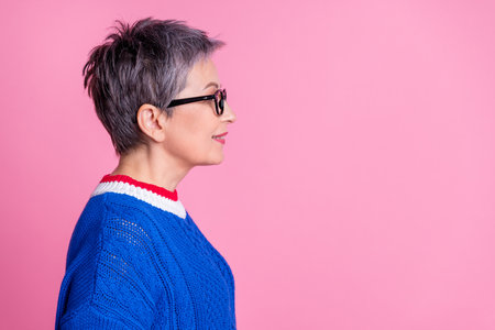 Profile photo of nice aged lady look empty space wear blue sweater isolated on pink color backgroundの写真素材