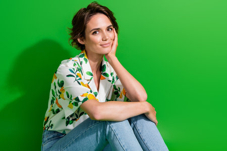 Portrait of young woman cute touch cheek pretty chic wear summer season shirt with orange fruit print isolated on green color backgroundの写真素材