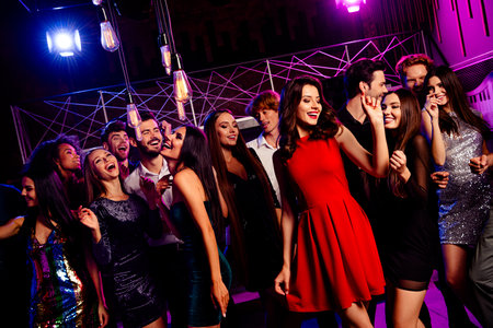 Energetic party crowd at stylish club with dancing and smiles as friends celebrate together in a neon nightclub vibeの写真素材