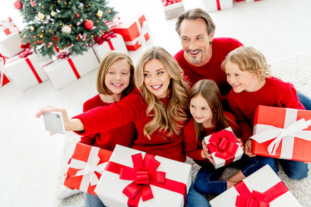 joyful family selfie with beautifully wrapped gifts by a decorated christmas tree at home during a festive christmas eve momentの写真素材