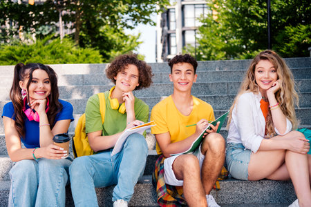 Group of cheerful teens studying outdoors in a sunny city park during summerの写真素材