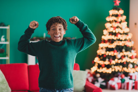 Happy boy in festive home with Christmas tree and cozy decor celebrating the holiday season with joy and excitementの写真素材