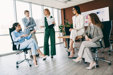 Diverse group of professionals discussing a project in a modern office setting promoting teamwork and collaborationの写真素材