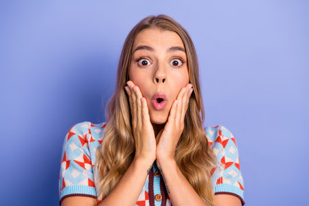Young woman with surprised joyful expression on purple background wearing a colorful cardigan for lifestyle fashion advertisingの写真素材
