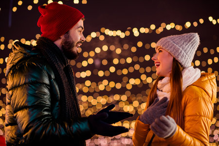 Playful winter chat under festive lights a couple shares warm merry moment in city market sceneの写真素材
