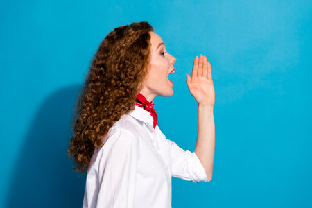 Profile side photo of funny lovely nice girl wear trendy white clothes speak loud look empty space isolated on blue color backgroundの写真素材