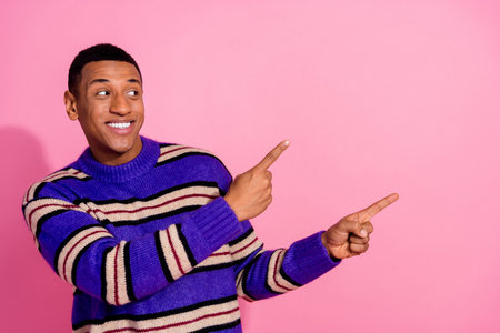 Photo of dreamy funny guy dressed striped pullover looking pointing two fingers empty space isolated pink color backgroundの写真素材
