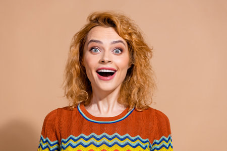 Portrait of impressed ecstatic girl with ginger hairdo wear knit t-shirt astonished staring isolated on beige color backgroundの写真素材