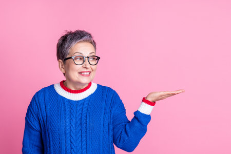 Photo of nice attrctive lovely senior woman wear trendy blue clothes hold product empty space isolated on pink color backgroundの写真素材