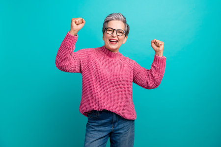 Portrait of overjoyed funky woman wear pink pullover in eyewear clenching fists win lottery isolated on turquoise color backgroundの写真素材