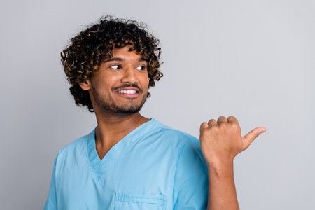 Photo of doctor guy look point finger empty space isolated grey color backgroundの写真素材