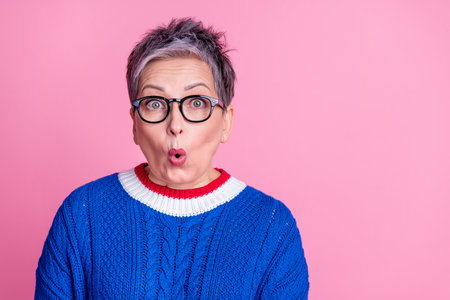 Photo of nice aged lady open mouth empty space wear blue sweater isolated on pink color backgroundの写真素材