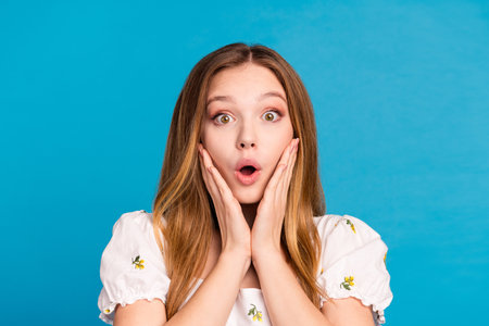 Photo of shocked girl hands touch face look impressed isolated blue color backgroundの写真素材
