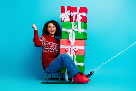 Young woman and girl share a joyful Christmas moment with colorful gift boxes stacked on a sleigh...