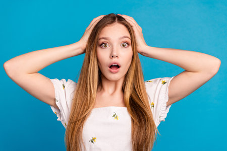 Photo of girls hands head look impressed isolated blue color backgroundの写真素材