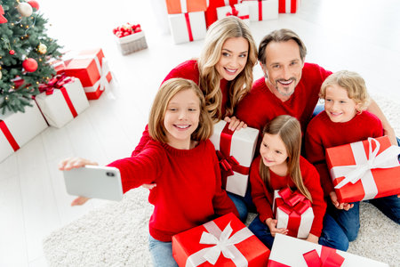 Family celebrates Christmas at home with gifts smiling faces and festive decor during a cozy indoor gatheringの写真素材