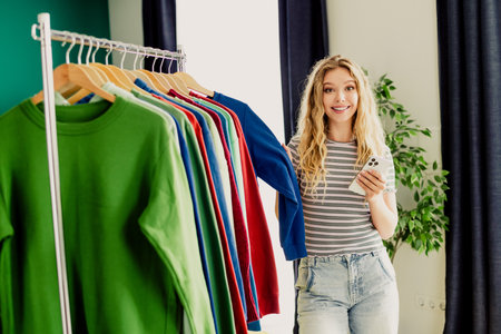Bright woman browses colorful clothes at home smiling beside a rack of shirts in a sunny living room