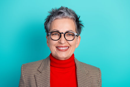 A mature female business professional smiles warmly in a casual yet polished outfit. The image...
