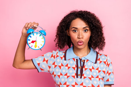 Vibrant portrait of a young woman with curly hair wearing a geometric knit shirt, holding a blue...