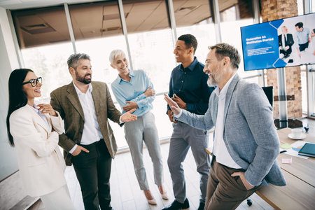 A group of professionally dressed coworkers enjoying discussion and cooperation in a contemporary office setting, fostering teamwork
