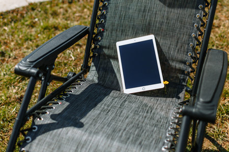 A folding black chair with a clipboard on it, standing on the spring grass. Vacation spot for a summer residentの写真素材