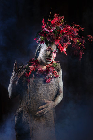 A girl smeared with clay. The model has a headdress made of flowers.の写真素材