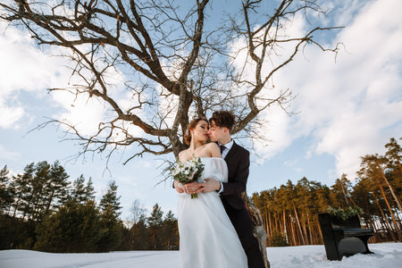 Two lovers standing in a winter forest against the background of the sunset.の写真素材