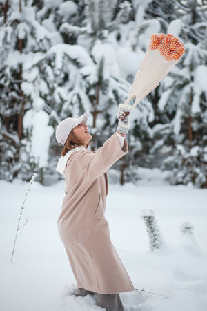 A girl in a winter forest with a bag of tangerines, walking through snowの写真素材