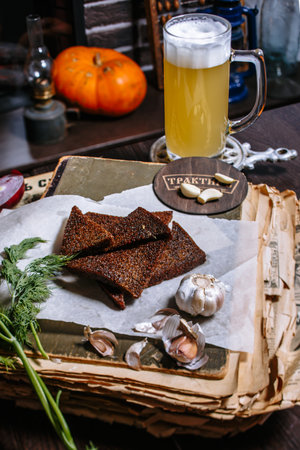 Fried black bread in the form of toast, lying on the table of the tavern. Next to dill, garlic, beer.の写真素材