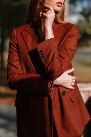 The girl is a model showing fashionable outerwear on the street, on the veranda of a summer cafe.の写真素材