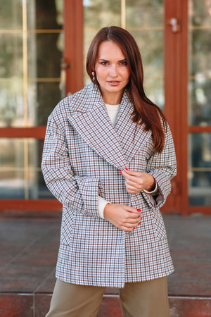 The girl is a model showing fashionable outerwear on the street, on the veranda of a summer cafe.の写真素材
