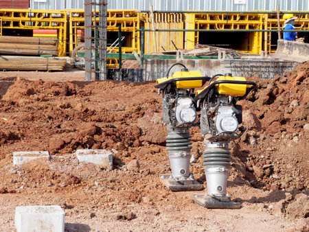 Construction worker compacting soil in house foundation using compactor