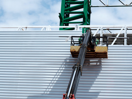 Construction worker at construction site using lifting boom machinery