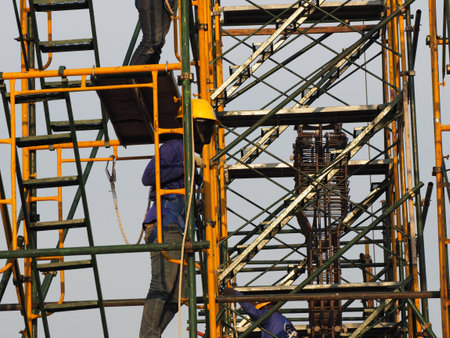 Construction workers working on scaffolding with blue sky at construction site
