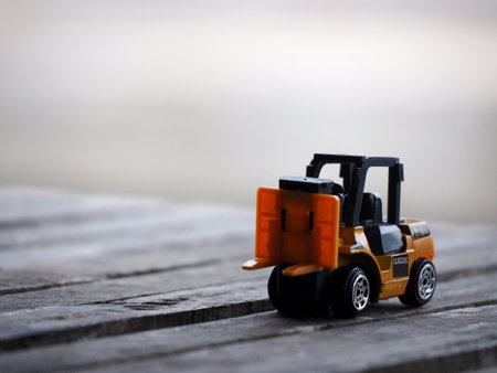 Miniature yellow forklift model on wooden table. Warehouse logistics business or construction industry conceptの写真素材
