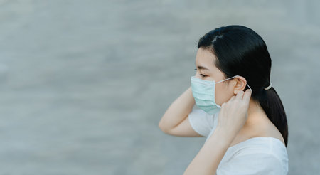 Asian woman wearing a surgical face mask protect herself from COVID19 pandemic with copy space.の写真素材