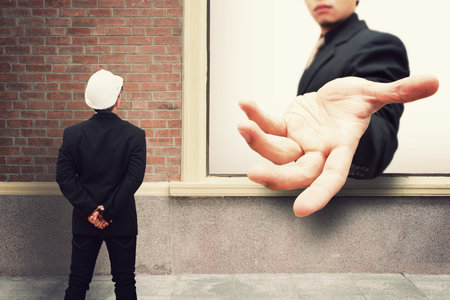 Business man give the hand through the wall for help order command Boss conceptの写真素材
