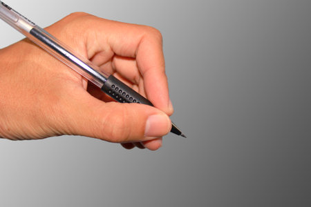 Hand holding a pen in business on grey wall 