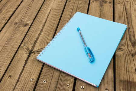 Blue notebook and pen on wood backgroundの写真素材