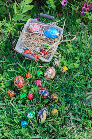 Diverse Easter eggs in a basket, placed on a grassの写真素材