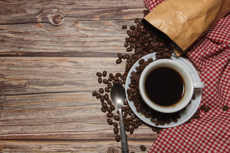 Coffee cups and coffee beans and red plaid cloth on a wooden background,top view,copy spaceの写真素材