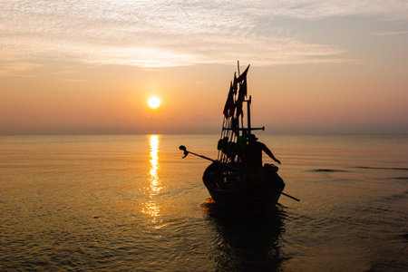 Silhouette of two people on a fishing boat that is about to go fishing in the morning sun.copy...