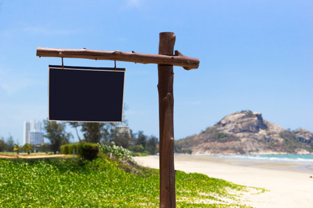 Wooden signboard on the coast with a background of mountains, sea and blue skyの写真素材