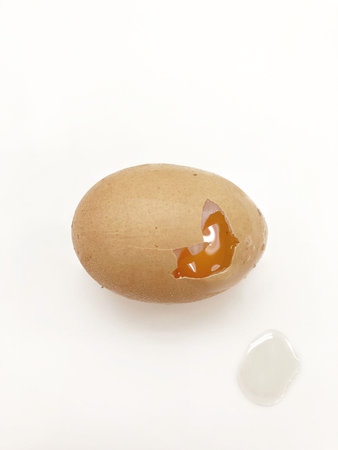 One raw egg is cracked on white