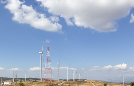 Wind turbines produce clean energy electricity on the backdrop of blue skies and clouds.