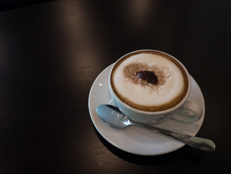 Frothy coffee and stainless steel spoons are placed on the table in the coffee shop.copy spaceの写真素材
