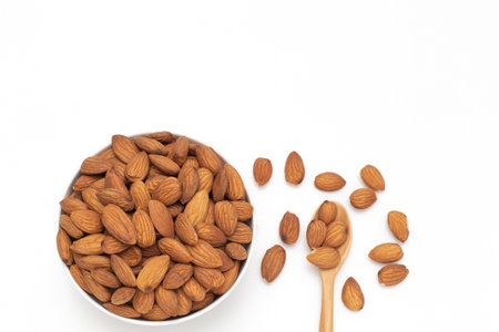 Almond nuts in white crockery with wooden spoon on isolate white background,top view,flat lay,top down,selective focus.の写真素材
