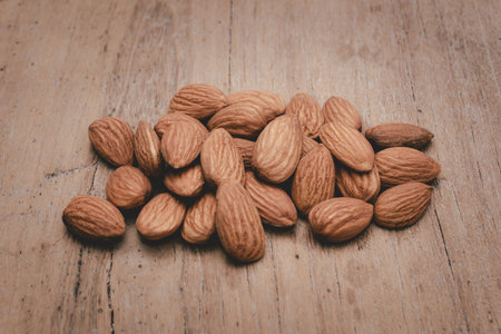 Almonds are placed on the wooden floor at the center of the image, copy space.の写真素材
