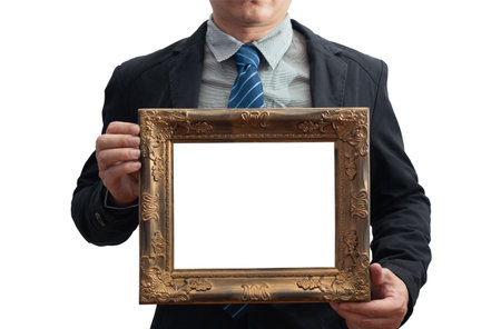 A blank diploma or a mockup certificate in the hand of a male employee wearing a black suit on white background with a clipping path. The horizontal picture frame is empty and the copy space. selective focus.の写真素材